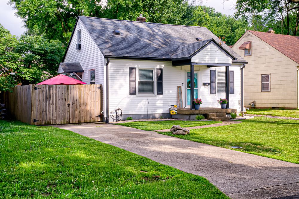 A white cottage-style home with a teal front door